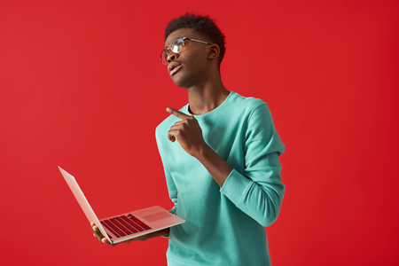 Young African American man in glasses standing with laptopの写真素材