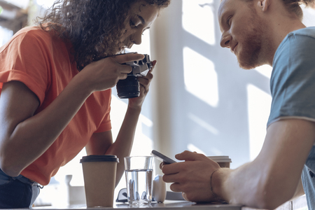 Young couple is using camera and phone in cafe