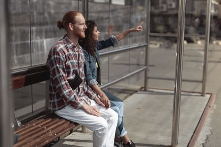 Happy young people are waiting for public transport outdoorの写真素材