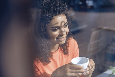 Cheerful young woman is relaxing with cup of coffeeの写真素材