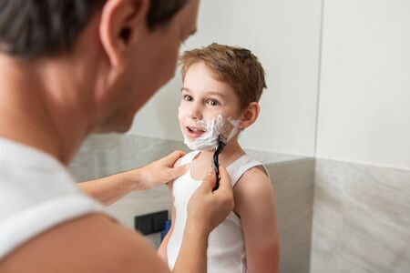 Father and son shaving together in bathroom at homeの写真素材