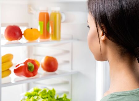 Young lady looking at fresh food in refrigeratorの写真素材