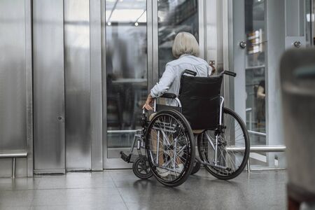 Adult woman on disabled carriage waiting for liftの写真素材
