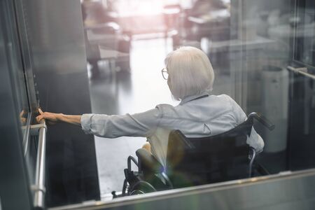 Mature woman on disabled carriage using lift