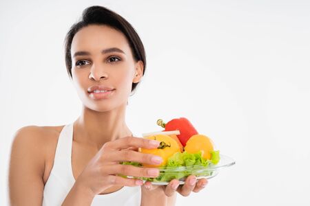 Smiling slender lady holding plate with vegetables