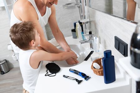 Father and son are standing in the bathroom at homeの写真素材