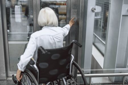 Old woman on disabled carriage using elevatorの写真素材
