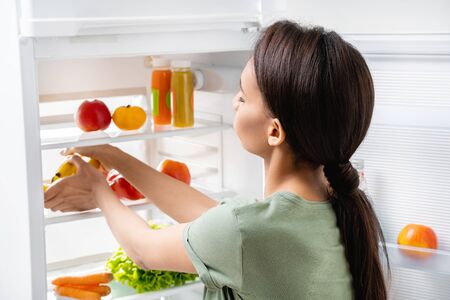Young pretty lady taking bananas from refrigeratorの写真素材