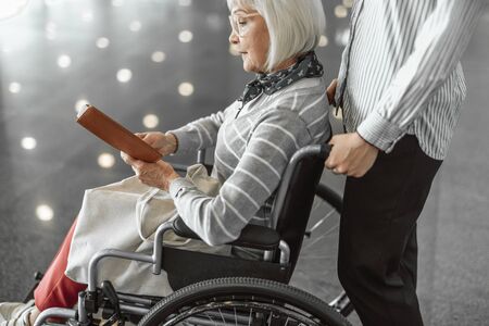 Female worker of airport moving wheelchair with elderly ladyの写真素材