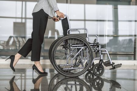 Woman holding empty wheelchair in the hall
