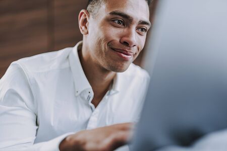 Joyful guy is entertaining with laptop at home