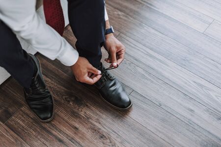 Executive is putting on loafers inside apartment