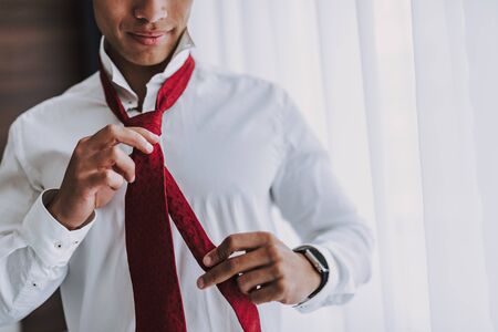 Smiling man is getting dressed before business meeting
