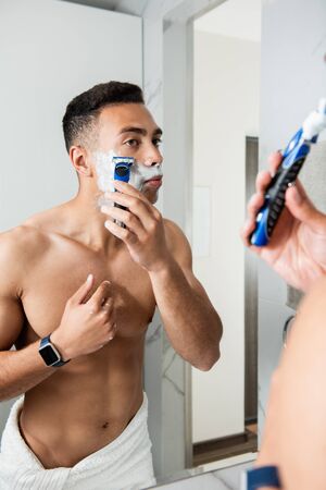 Naked muscular man shaving himself by razorの写真素材
