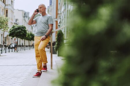 Adult gray-haired man is standing outdoors in the cityの写真素材