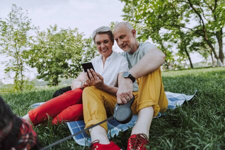 Smiling adult man and woman resting in the park with dogsの写真素材