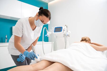 Cropped photo of female legs during vacuum roller massage procedure in clinic