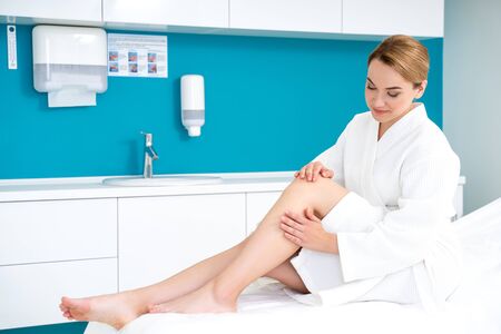 Contented woman touching her smooth legs and smiling