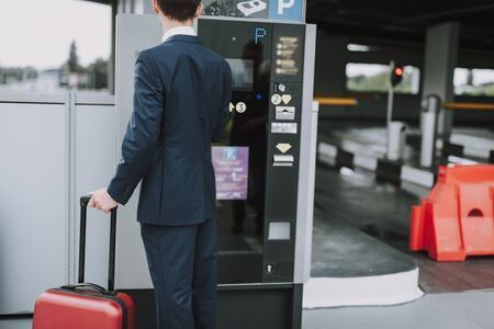 Young guy in suit paying for parking outdoorsの写真素材