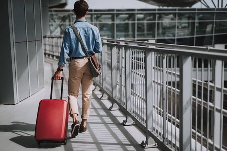 Young guy in casual wear walking in airportの写真素材