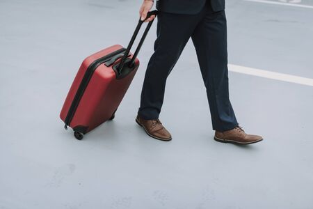 Man with suitcase walking on the parking lot outdoorsの写真素材