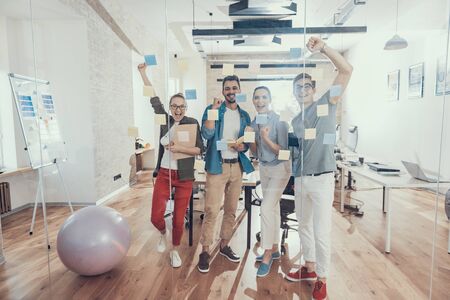 Four smiling partners are enjoying their work together in office