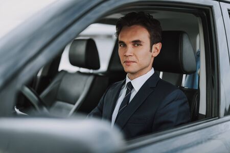 Happy man in black costume sitting in carの写真素材