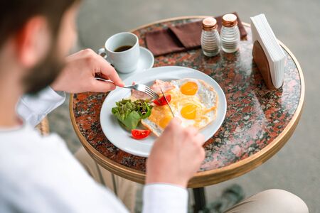 Bearded young man having breakfast on terraceの写真素材