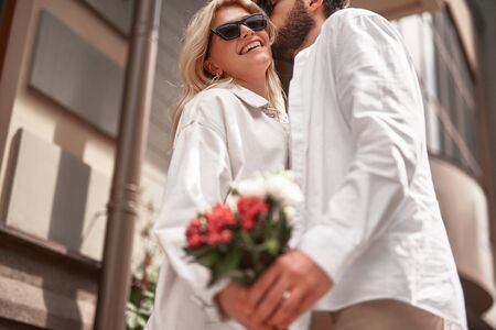 Smiling lady with flowers smiling while hugging her boyfriendの写真素材