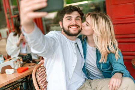 Young couple with smartphone sitting in cafe outdoorsの写真素材