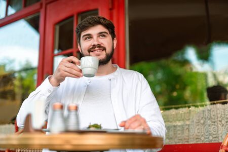 Portrait of happy man sitting at cafe and smiling