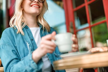 Happy woman enjoying hot drink in outdoor cafeの写真素材