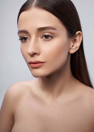 Beautiful young woman with perfect skin standing against light blue backgroundの写真素材