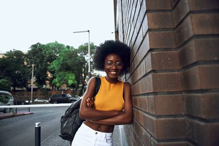 Happy pretty woman leaning on brick wall on the streetの写真素材
