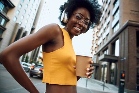 Happy afro-american female holding hot drink outdoorsの写真素材