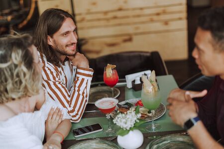 Three friends chatting and enjoying cocktails in cafeの写真素材