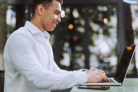 Handsome young man in white shirt using laptopの写真素材