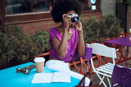 Young afro-american woman is using retro cameraの写真素材