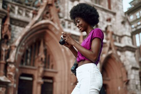 Afro-american lady standing on the street with cameraの写真素材