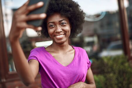 Happy young afro-american woman using smartphone outdoorsの写真素材