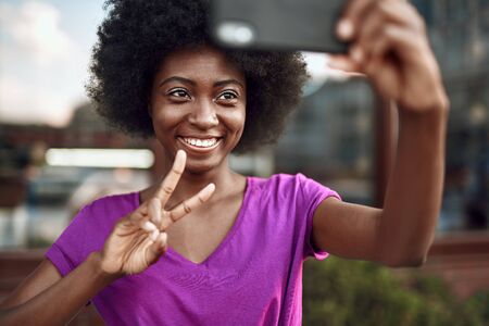 Smiling afro-american lady using mobile phone outdoorsの写真素材