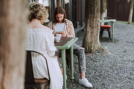 Young man using cellphone while spending time with friendの写真素材