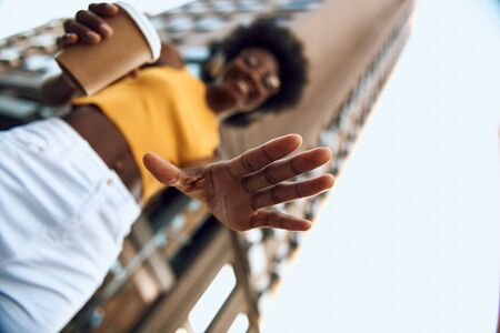 Similing afro-american female holding hot drink in the cityの写真素材
