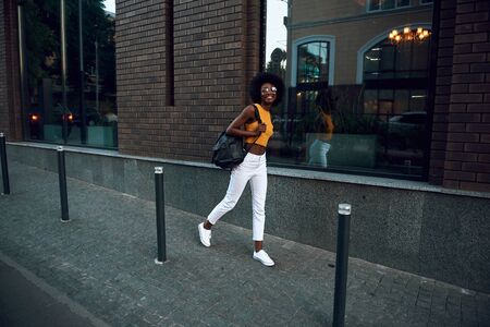 Pretty and smiling afro-american woman walking outsideの写真素材