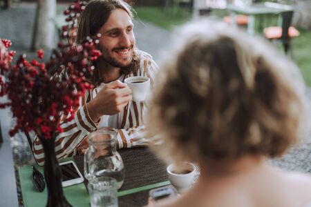 Joyful young man enjoying coffee in outdoor cafe