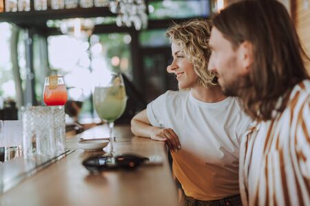 Beautiful couple sitting at the bar counter with cocktailsの写真素材