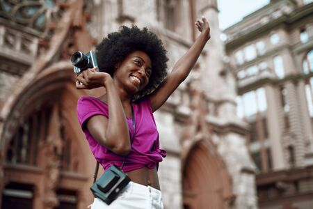 Happy afro-american woman is holding retro cameraの写真素材