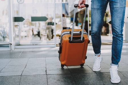 Close-up of man walking with suitcase. He is going in departure lounge. Copy space in left sideの写真素材