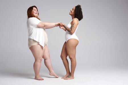 Couple of fat female friends holding hands in studioの写真素材
