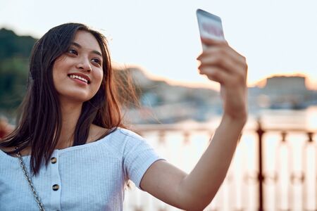 Happy asian lady making selfie on bridgeの写真素材